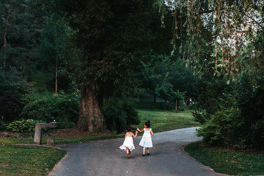 dwie dziewczynki dzieci biegn przez zielony park w lecie